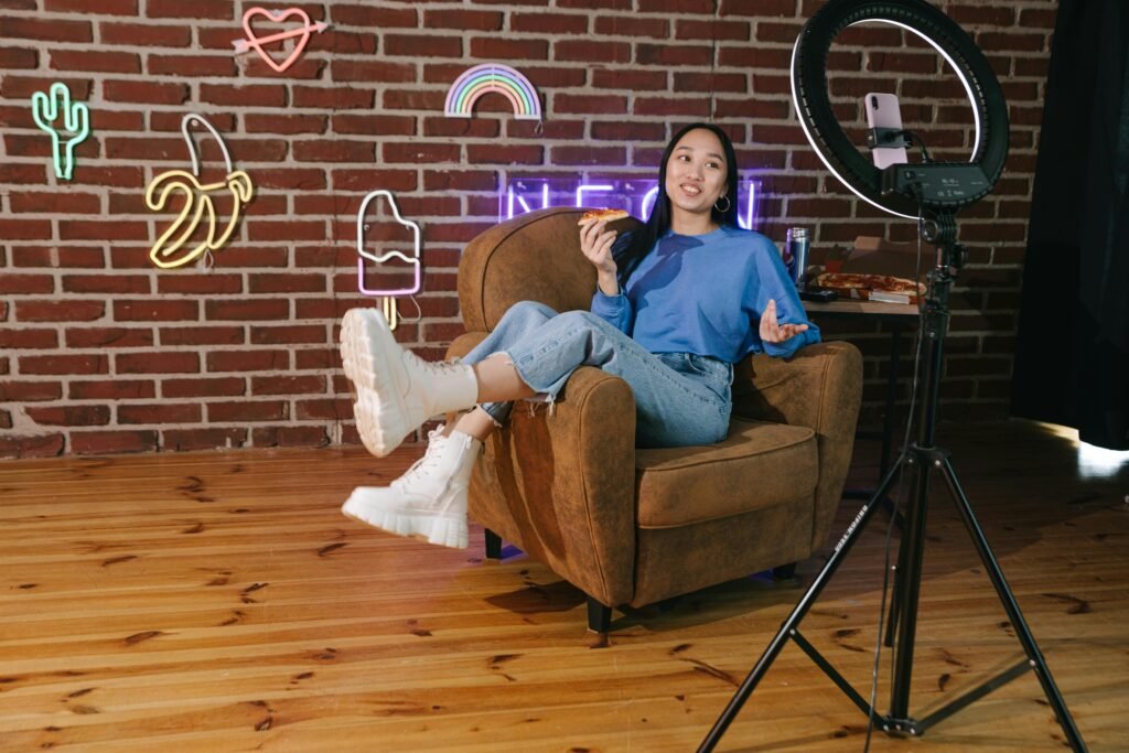 micro-influencer lounging in a chair while filming themselves from a phone attached to a ring light.